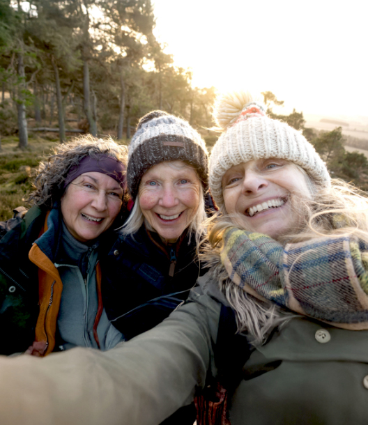 Selfie of three smiling women on a sunny, wintery hike